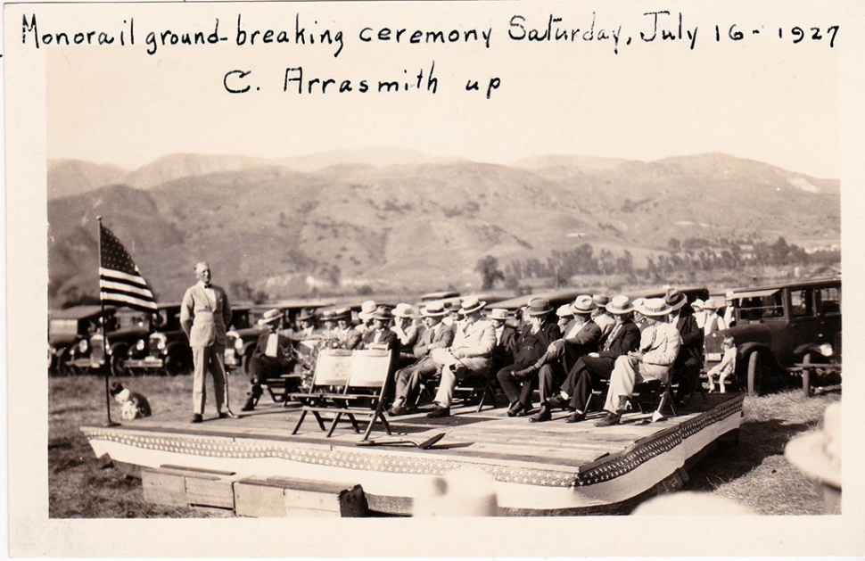 Groundbreaking ceremony for the Fillmore Mononrail which took place July 7th 1927. Pictured is Clarence Arrasmith, City Manager, standing. Seated L to R: Dock Wyatt (Santa Paula); Mayor W. H. Price; P. S. Coombs, VP Sespe Development Company; J. O. Groves, head engineer, Sespe Development Company; Joseph McNab, chairman of the ceremony; David J. Reese, Ed Goodenough; reporters. 
