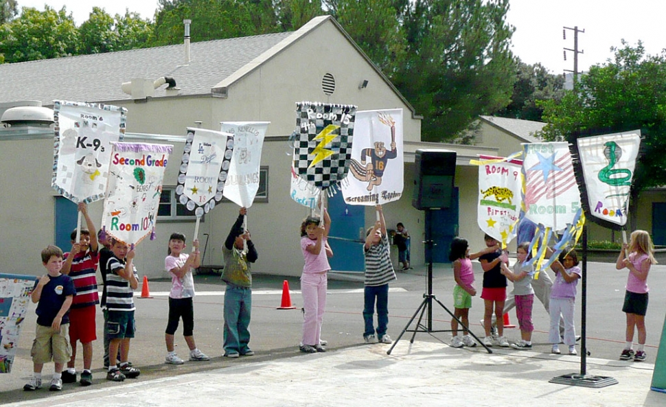 (Above) Opening Ceremony with class banners of the Piru Elementary Olympics. “Citius, Altius, Fortius,” last week the Olympic Motto came to life for students at Piru Elementary as they reached for “swifter, higher, and stronger” achievements in their school Olympics. After practicing at lunch recess for weeks at their Olympic Training Center the student athletes were ready to meet the competition. The Games began with a grand procession of classes around the athletic field to the Opening Ceremonies. While their class banners proclaimed their class’ presence students were welcomed to the competition in the spirit of the Olympics. Following the lighting of the Olympic flame the opening day competition began.  To classmate cheers athletes pulled with all their strength in the tug-of-war competition and later ran swiftly in a shortened marathon. Winners were awarded “Olympic” medals for their success. Throughout the week at lunch recess the competition continued when grade levels vied for soccer medals.  Piru’s Olympic Games culminated Friday afternoon as individual students and teams gave their best as they struggled for success in long jump, shot put, jump rope, hula hoop, Frisbee throw, and running relay. As the games drew to a close every student had an opportunity to compete to the encouragement of his or her classmates. And, Piru Elementary School echoed with the pleasure of its students.