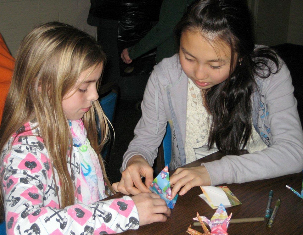 Japanese exchange student Nanako Matsumoto shows Chloe Stines how to transform her paper into an origami crane at a recent Bardsdale 4-H meeting.