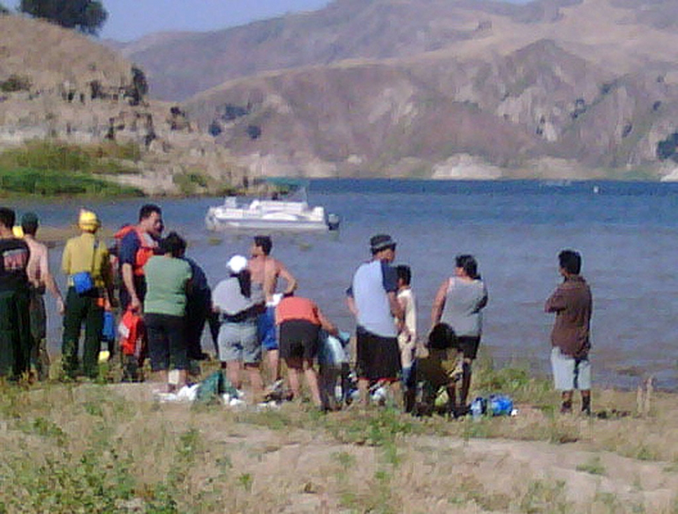A crowd gathers to watch the attempted rescue of Denise Arredondo, of Piru, Saturday. Denise drowned after wading into the lake while on a family picnic.