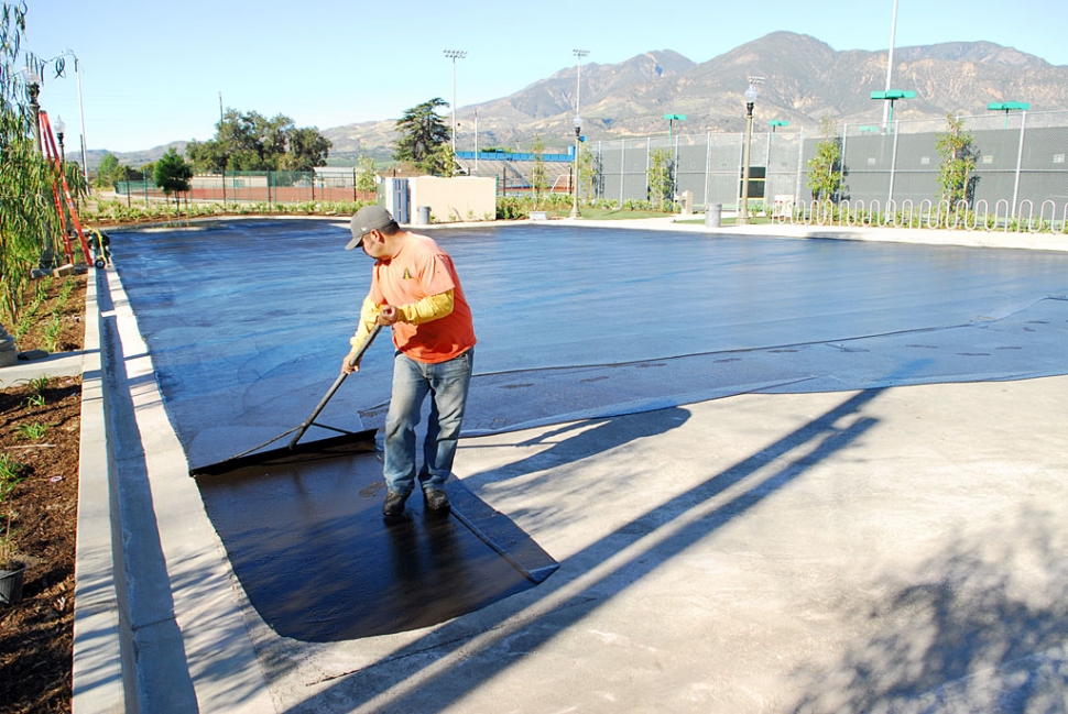 A worker seals the asphalt at the new swimming complex on First Street.