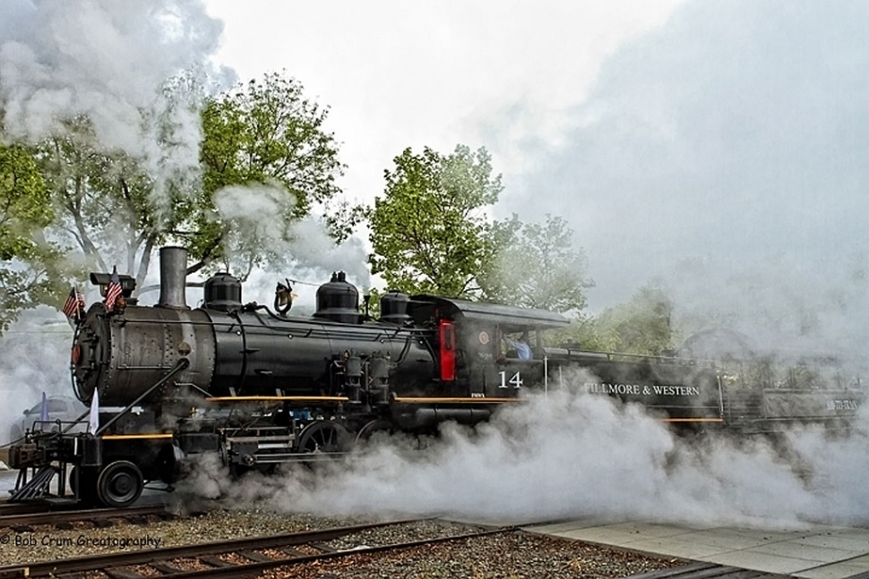 The annual RailFest attracts thousands of visitors from all over southern California and in spite of less then desirable weather opening day... this years festival was no exception. But this year there was an exceptional reason for perhaps more folks than normal to drive for hours to be there. The reason being a very special refurbished locomotive recently completed and put on line. She's big... black... and oh-so-very addictive. 

The Queen of the 2011 RailFest is a recently restored Baldwin 2-8-0 steam locomotive titled #14... also affectionately known as Tresa Jean. #14 was born in 1913 in a Baldwin Locomotive company factory. She last revenue service in the 1960s and was parked in a RR yard until bought by the Fillmore & Western RR in 1999 from the Dodge City RR in Kansas. Because you can't just buy spare parts for an 86-year old steam engine, it's been a huge project. Now fully restored, Dave Wilkerson, FWRY owner, says that #14 is the only full-size operating steam engine in Southern California. 

Steam locomotive buffs have been waiting for some time for this glorious occasion. When it was announced to the world that #14 would be working... pulling rolling stock... steam engine aficionados from everywhere flocked to Central Park. And if I had a quarter for every photo taken of #14 over the RailFest weekend... I'd have more money than was won in the last Mega Million lotto. You simply cannot look at her and not be mesmerized. And fascinated! And does she ever love to show off... belching smoke from her lovely stack to blasting steam to let everyone know exactly what makes her so very special. Her bell rings crystal clear and the whistle is a sound to behold. 

The steam-powered train ride took passengers east out to Fish Hatchery Road with a special treat on the way back. After passing through the infamous Fillmore tunnel... the engineer stopped the train to allow photographers to disembark. The train then backed up and then came back through the tunnel... belching smoke high into the air and blasting steam! Photographers were ecstatic as #14 displayed her majesty and magic. Did I say that she loves to show off? 

As always, the Fillmore RailFest... sponsored by the Santa Clara River Valley Railroad Historical Society and the Fillmore & Western Railroad... is a crowd pleasing family event. Besides the regularly featured train rides, there were 'speeder' rides, antique farm equipment, great Historical Society tri-tip bar-b-que, kids rides, down-home music, arts & crafts booths, and the ever entertaining Frontier Gunfighters who also 'robbed' the steam train of bags of loot. Where's the sheriff when ya need him? 

When the day is done... and one has participated in all the marvelous activities and events of the Fillmore RailFest... one sighs and declares... WOW.. that was FUN! See you next year! In the meantime... we'll leave the boiler on for ya!