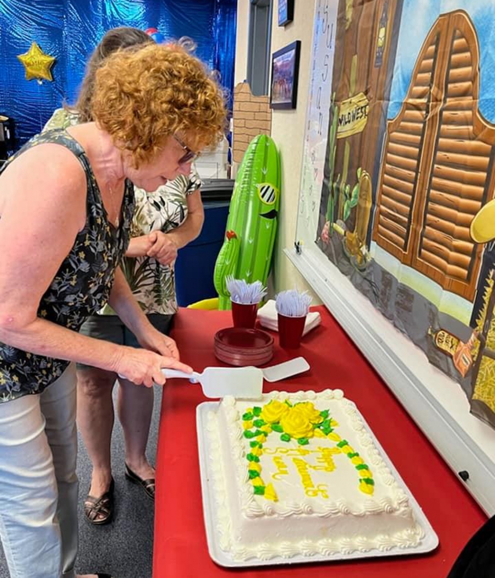 Mrs. Fitzgerald doing the honors of cutting her cake in celebration of her retirement.