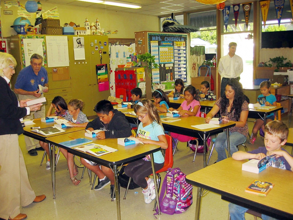 Rotarians Ruth & Don Gunderson and Sean Morris share student dictionaries with students.