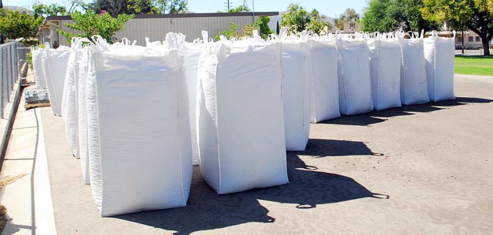 Truckloads of rubberized mulch made their way into Fillmore last week to replace the aged woodchips at the district’s elementary school playgrounds. Sespe, Piru, and San Cayetano will all benefit from the recyclable rubber, made from 45,000 old tires, shown in packages stored at the district. A grant of $144,000 provided for the mulch, according to Denise Berrington, facilities secretary at the Fillmore Unified School District. Piru Elementary’s chips have already been replaced with blue rubberized mulch, and Sespe and San Cayetano are next, opting for the more natural looking cypress red shade. The mulch provides maximum fall protection for students on the playground.