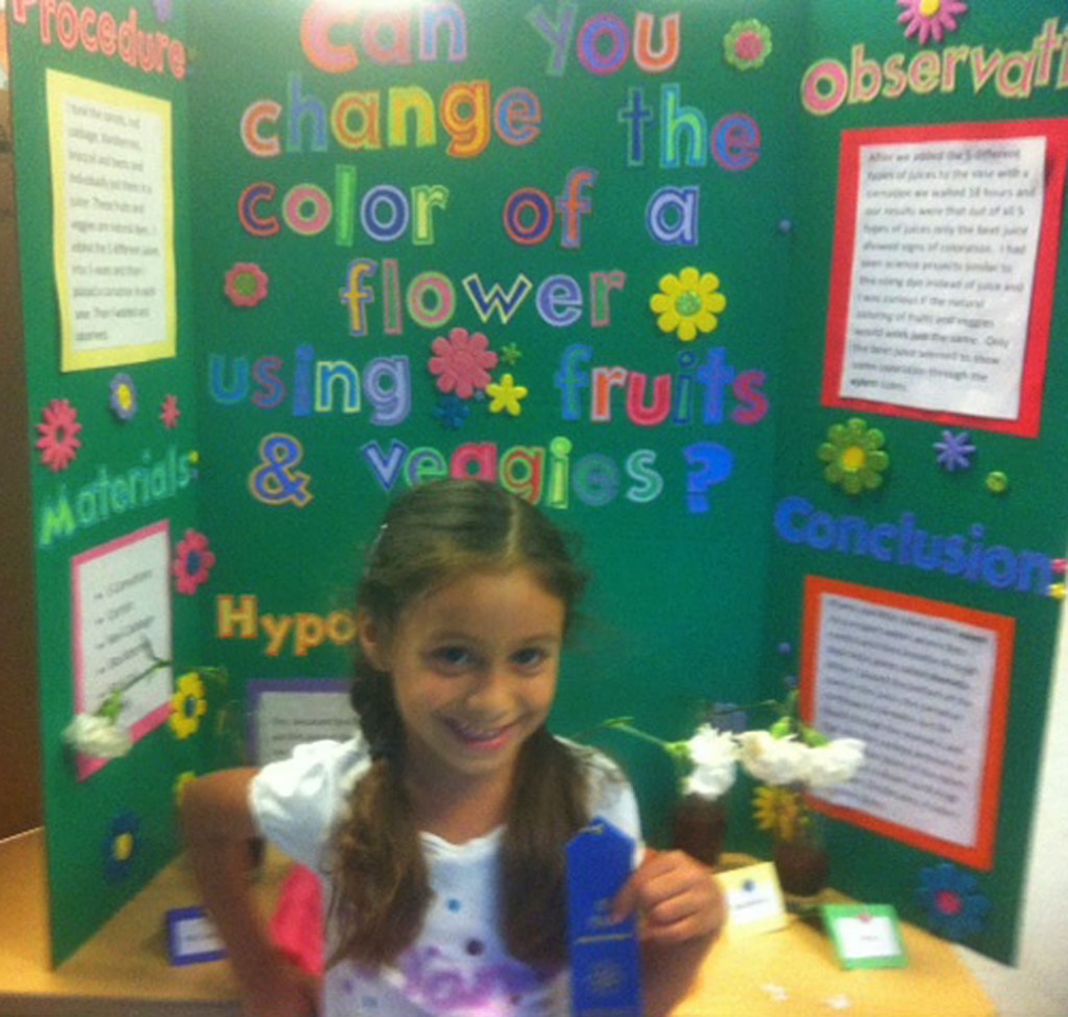 Lexie Gonzales, Sespe School kindergarten, stands next to her experiment, “Can You Change the Color of a Flower Using Fruits and Vegetables?”  Using the scientific method and “green” chemicals, Lexie is on track for a promising future.