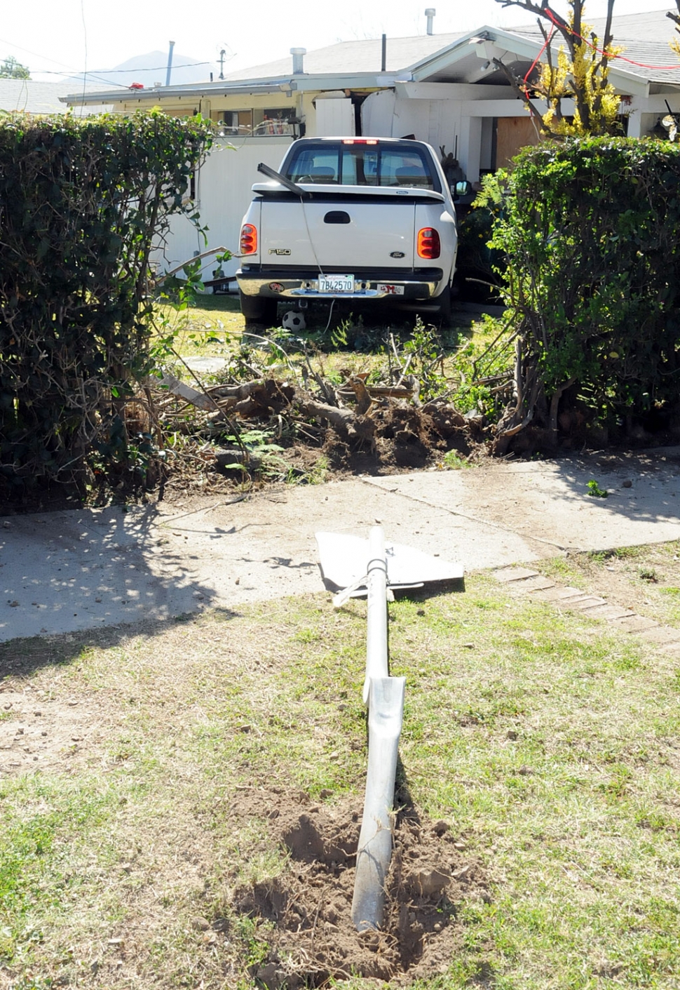 The truck jumped the curb, flattened a stop sign, crashed through a hedge and struck a house, causing significant damage. 